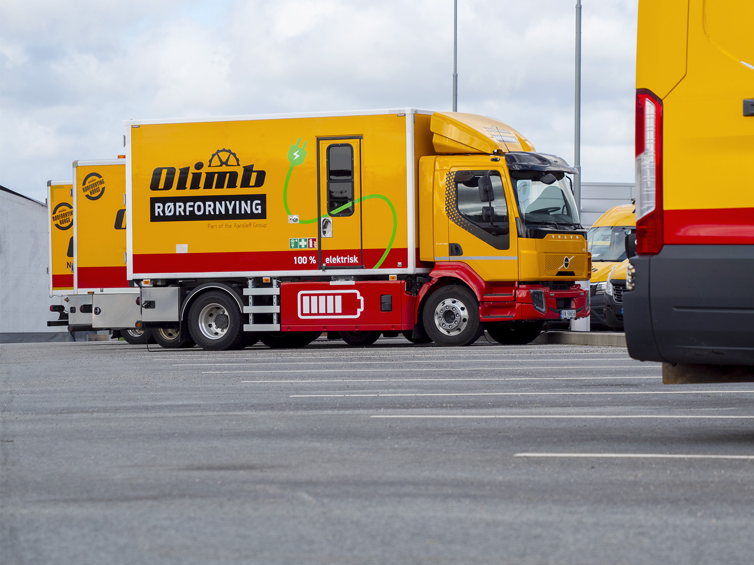En av Olimb Rørfornyings nye, helelektriske Volvo FL Electric spesialbiler i gult og rødt, parkert utendørs.